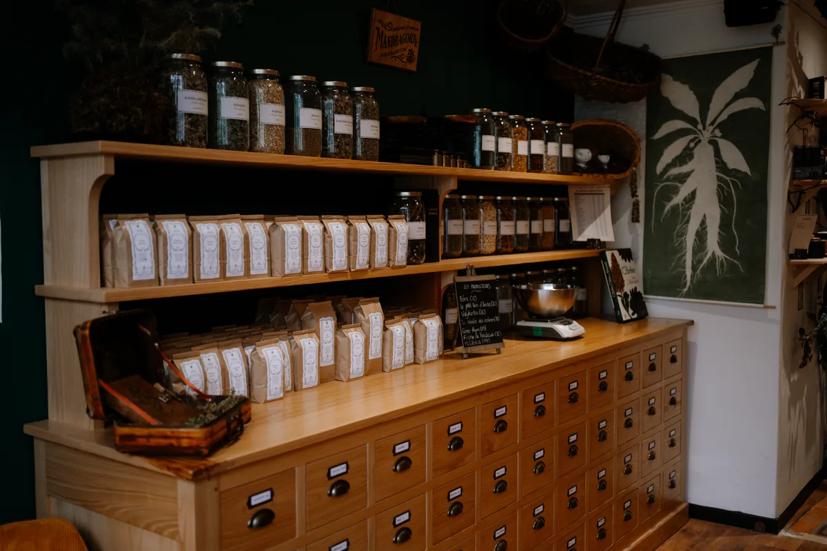 Comptoir à tiroirs d'apothicaire de l'herboristerie Mandragora, bocaux de plantes et sachets de tisanes